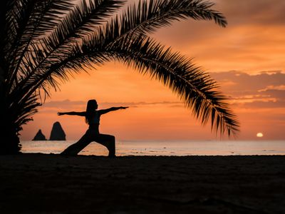Silhouette of a person in a power yoga pose at sunset.